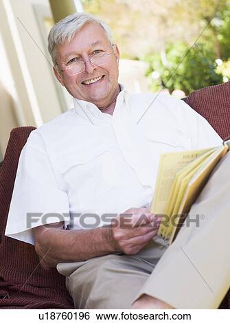 Senior woman sitting outdoors on a chair reading a book View Large Photo Image Stock Photograph - Senior woman sitting outdoors on a chair reading a book. Fotosearch
