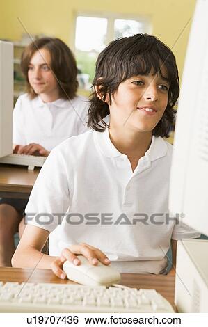Stock Photograph - Student at computer terminal with student in background (selective focus). Fotosearch