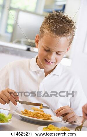 Stock Image - Student in cafeteria eating lunch (selective focus). Fotosearch
