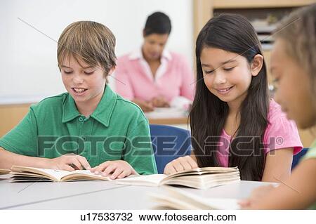 Students in class reading with teacher in background (selective focus) View Large Photo Image Stock Image - Students in class reading with teacher in background (selective focus). Fotosearch