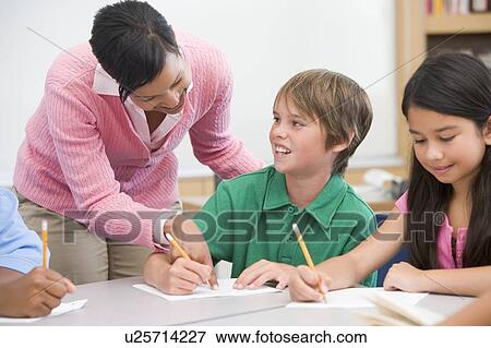 Students in class writing with teacher helping View Large Photo Image Stock Photo - Students in class writing with teacher helping. Fotosearch