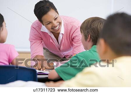Stock Image - Teacher helping student in class (selective focus). Fotosearch