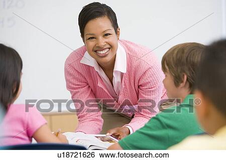 Stock Photograph - Teacher helping student in class (selective focus). Fotosearch