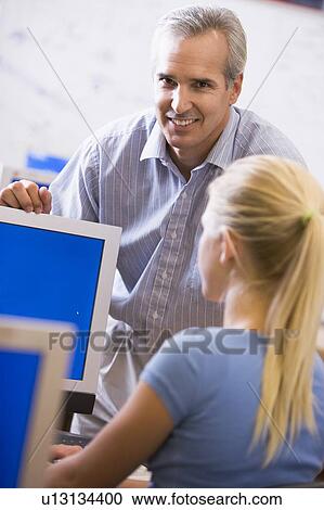 Teacher with female student in computer class View Large Photo Image Stock Image - Teacher with female student in computer class. Fotosearch