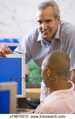 Teacher with male student in computer class View Large Photo Image Stock Image - Teacher with male student in computer class. Fotosearch