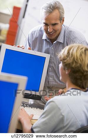 Stock Photo - Teacher with male student in computer class. Fotosearch
