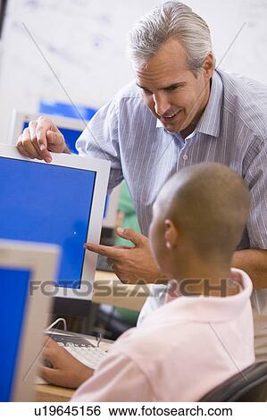 Teacher with male student in computer class View Large Photo Image Stock Photograph - Teacher with male student in computer class. Fotosearch
