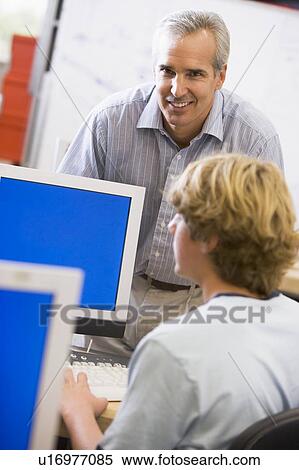 Stock Photography - Teacher with male student in computer class. Fotosearch