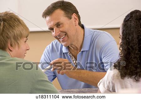 Picture - Teacher with two students in classroom. Fotosearch