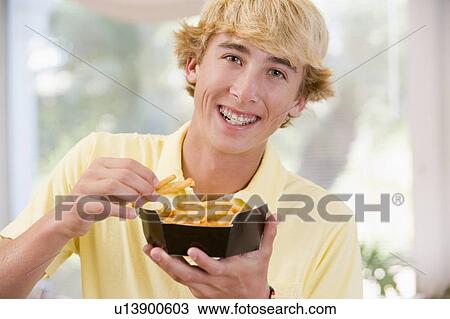 Stock Image - Teenage Boy Eating French Fries . Fotosearch