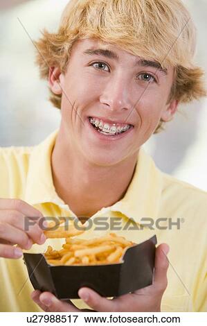 Stock Photo - Teenage Boy Eating French Fries . Fotosearch