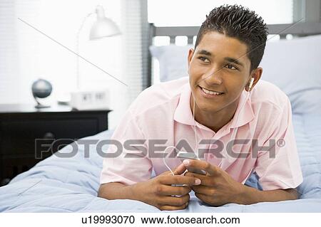 Teenage Boy Lying On Bed Listening To Mp3 Player View Large Photo Image Stock Image - Teenage Boy Lying On Bed Listening To Mp3 Player. Fotosearch