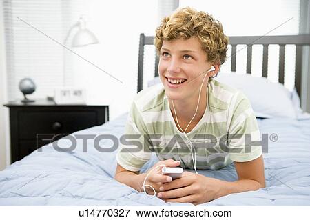 Teenage Boy Lying On Bed Listening To Mp3 Player View Large Photo Image Stock Photo - Teenage Boy Lying On Bed Listening To Mp3 Player. Fotosearch
