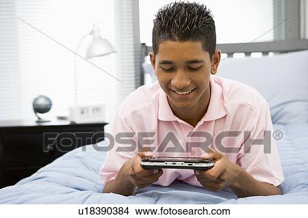 Teenage Boy Lying On Bed Playing Video Game View Large Photo Image Picture - Teenage Boy Lying On Bed Playing Video Game. Fotosearch