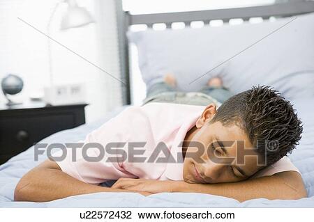 Stock Image - Teenage Boy Lying On Bed. Fotosearch