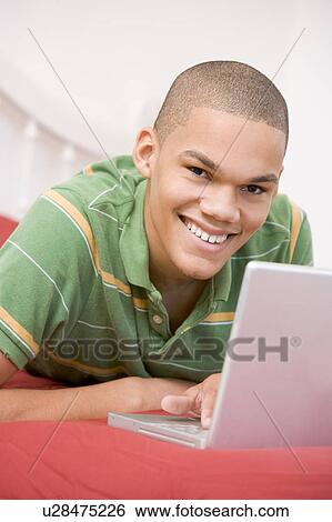 Teenage Boy Lying On Bed Using Laptop View Large Photo Image Stock Photograph - Teenage Boy Lying On Bed Using Laptop . Fotosearch