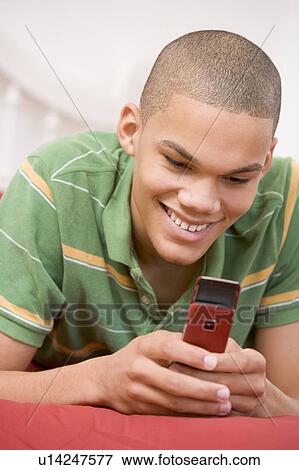 Stock Photo - Teenage Boy Lying On Bed Using Mobile Phone . Fotosearch