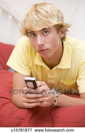Stock Photo - Teenage Boy Lying On Bed Using Mobile Phone . Fotosearch