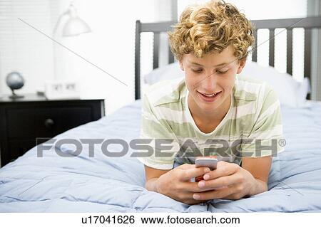 Teenage Boy Lying On Bed Using Mobile Phone View Large Photo Image Stock Photograph - Teenage Boy Lying On Bed Using Mobile Phone . Fotosearch