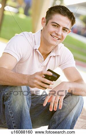 Teenage Boy Sitting Outdoors Using Mobile Phone View Large Photo Image Stock Image - Teenage Boy Sitting Outdoors Using Mobile Phone. Fotosearch