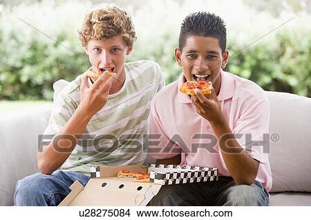 Picture - Teenage Boys Sitting On Couch Eating Pizza Together. Fotosearch
