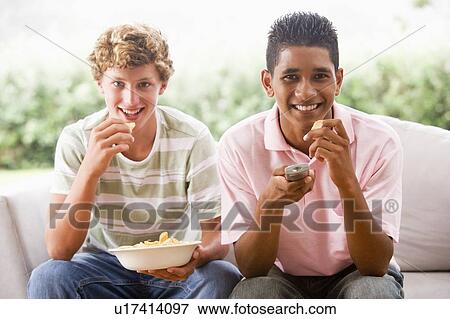 Teenage Boys Sitting On Couch Eating crisps Together View Large Photo Image Stock Photo - Teenage Boys Sitting On Couch Eating crisps Together. Fotosearch