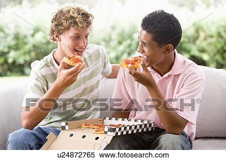 Stock Photography - Teenage Boys Sitting On Couch Eating Pizza Together. Fotosearch