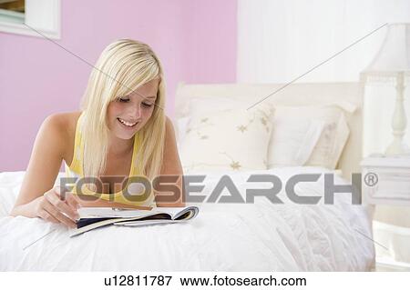 Stock Photo - Teenage Girl Lying On Bed Reading. Fotosearch