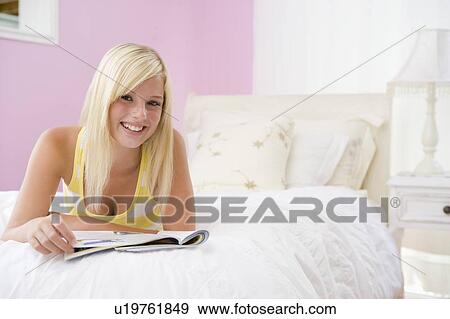 Stock Photo - Teenage Girl Lying On Bed Reading. Fotosearch