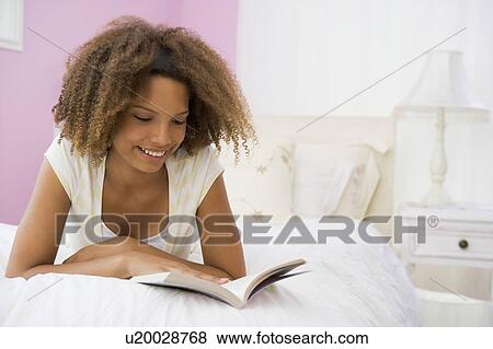 Stock Photo - Teenage Girl Lying On Bed Reading. Fotosearch
