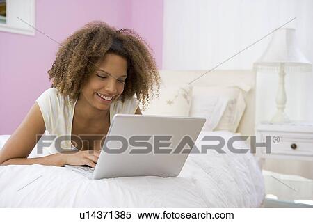 Teenage Girl Lying On Bed Using Laptop View Large Photo Image Stock Photography - Teenage Girl Lying On Bed Using Laptop . Fotosearch