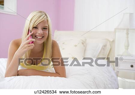 Picture - Teenage Girl Lying On Bed Using Mobile Phone . Fotosearch