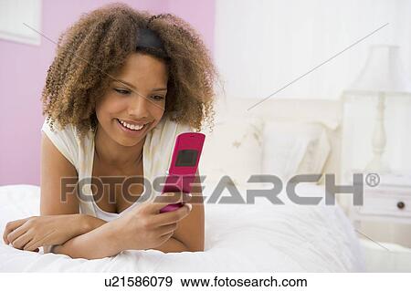Teenage Girl Lying On Bed Using Mobile Phone View Large Photo Image Stock Photo - Teenage Girl Lying On Bed Using Mobile Phone . Fotosearch