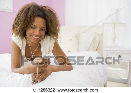Teenage Girl Lying On Bed Using Mp3 Player View Large Photo Image Stock Image - Teenage Girl Lying On Bed Using Mp3 Player. Fotosearch