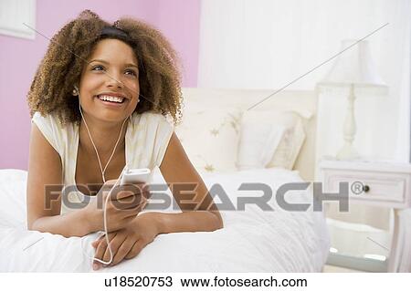 Teenage Girl Lying On Bed Using Mp3 Player View Large Photo Image Stock Image - Teenage Girl Lying On Bed Using Mp3 Player. Fotosearch