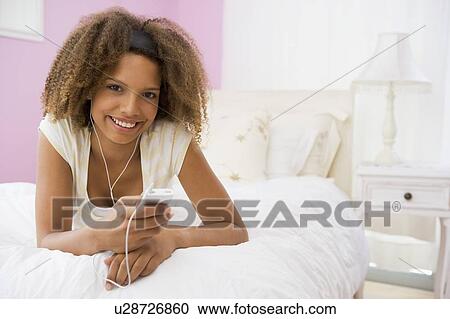 Teenage Girl Lying On Bed Using Mp3 Player View Large Photo Image Stock Image - Teenage Girl Lying On Bed Using Mp3 Player. Fotosearch