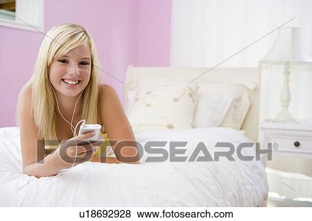 Teenage Girl Lying On Bed Using Mp3 Player View Large Photo Image Stock Photo - Teenage Girl Lying On Bed Using Mp3 Player. Fotosearch