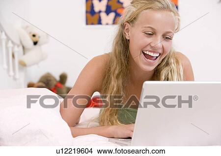 Teenage Girl Lying On Her Bed Using Laptop View Large Photo Image Picture - Teenage Girl Lying On Her Bed Using Laptop. Fotosearch
