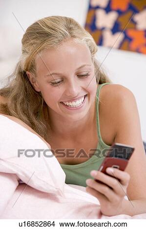 Teenage Girl Lying On Her Bed Using Mobile Phone View Large Photo Image Picture - Teenage Girl Lying On Her Bed Using Mobile Phone. Fotosearch