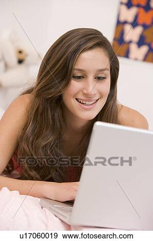 Teenage Girl Lying On Her Bed Using Laptop View Large Photo Image Stock Photo - Teenage Girl Lying On Her Bed Using Laptop. Fotosearch