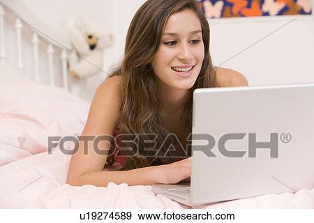 Teenage Girl Lying On Her Bed Using Laptop View Large Photo Image Stock Photo - Teenage Girl Lying On Her Bed Using Laptop. Fotosearch