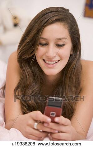 Teenage Girl Lying On Her Bed Using Mobile Phone View Large Photo Image Stock Photo - Teenage Girl Lying On Her Bed Using Mobile Phone. Fotosearch