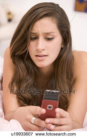 Teenage Girl Lying On Her Bed Using Mobile Phone View Large Photo Image Stock Photo - Teenage Girl Lying On Her Bed Using Mobile Phone. Fotosearch