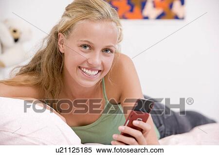 Teenage Girl Lying On Her Bed Using Mobile Phone View Large Photo Image Stock Photography - Teenage Girl Lying On Her Bed Using Mobile Phone. Fotosearch