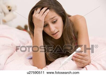 Stock Image - Teenage Girl Lying On Her Bed With A Pregnancy Test. Fotosearch