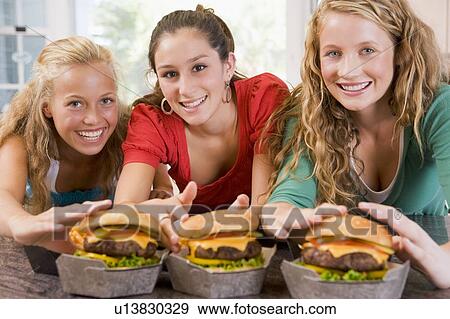 Stock Photo - Teenage Girls Eating Burgers . Fotosearch