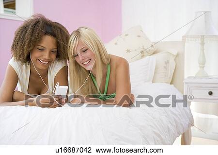 Teenage Girls Lying On Bed Listening To Mp3 Player View Large Photo Image Stock Image - Teenage Girls Lying On Bed Listening To Mp3 Player. Fotosearch
