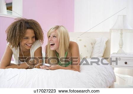 Teenage Girls Lying On Bed Listening To Mp3 Player View Large Photo Image Stock Image - Teenage Girls Lying On Bed Listening To Mp3 Player. Fotosearch