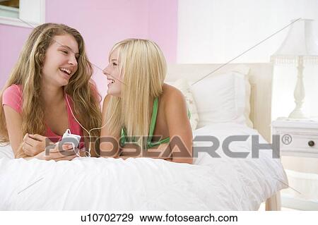 Teenage Girls Lying On Bed Listening To Mp3 Player View Large Photo Image Stock Photo - Teenage Girls Lying On Bed Listening To Mp3 Player. Fotosearch