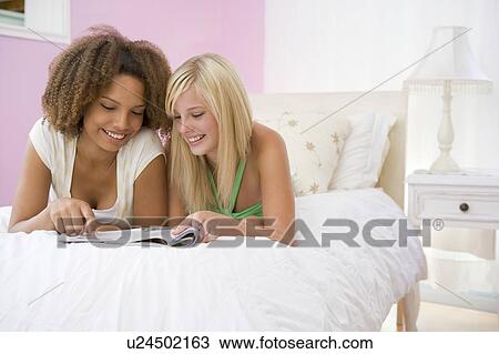 Stock Image - Teenage Girls Lying On Bed. Fotosearch